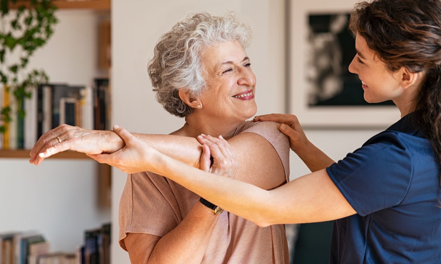 Senior woman doing arm exercises with caregiver