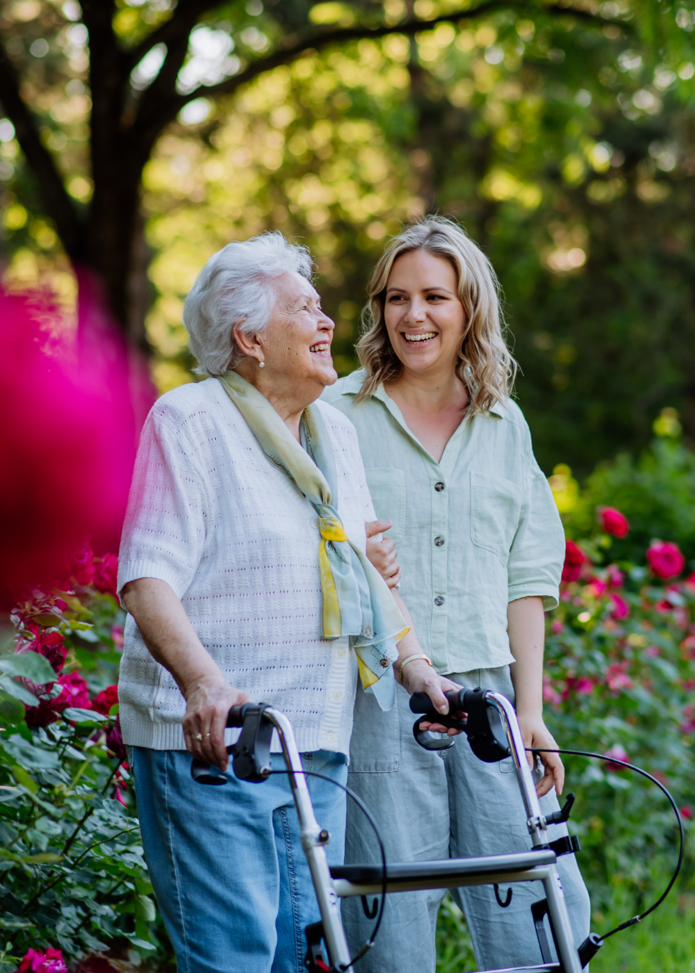 Elderly woman with walker and caregiver outdoors