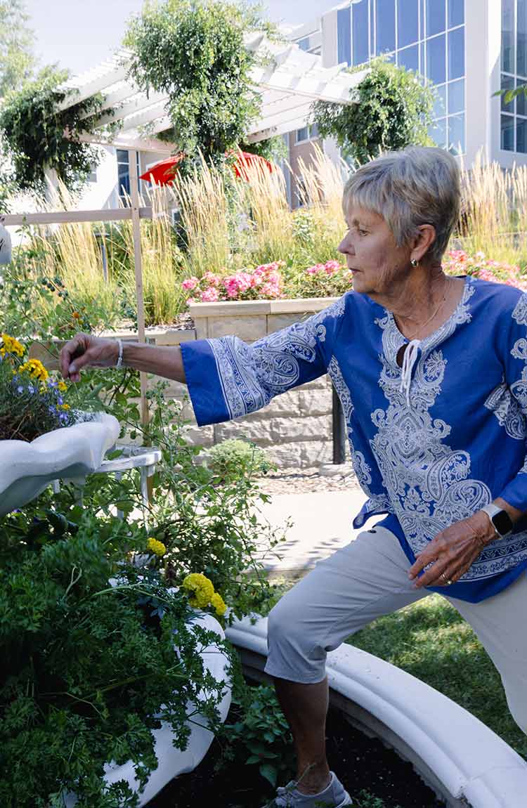 Resident caring for flowers in the outdoor garden at Cottage Grove Place
